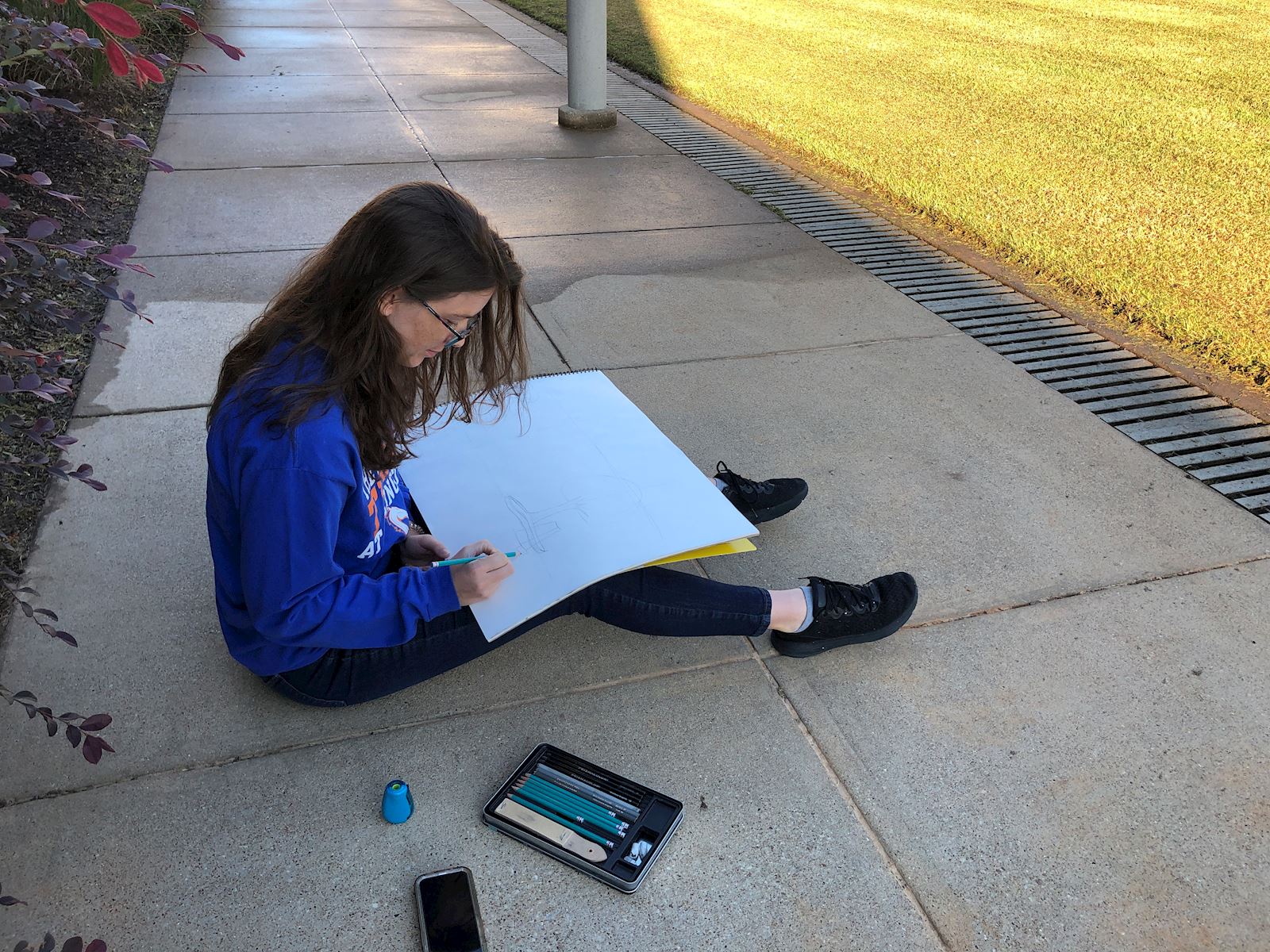 Student drawing on campus quad