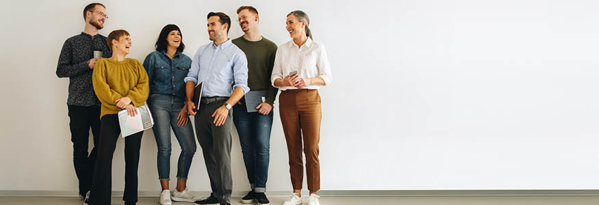 Colleagues talking while standing at wall. Happy creative team standing at wall and discussing.