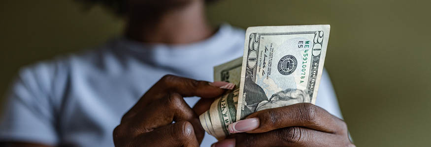 African American woman holding and counting dollars. Home budget planning.