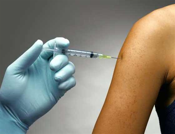 Bare arm receiving a shot with a syringe                                                                                                    
