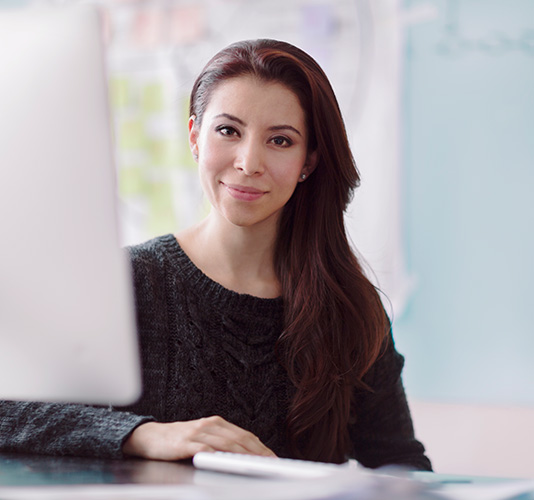 young woman sitting at a desk behind a computer                                                                                             