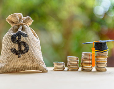 stacks of coins with a graduation cap