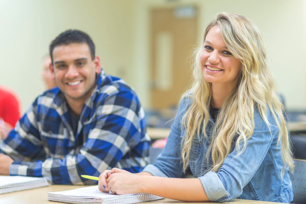 Two students smiling in classroom.