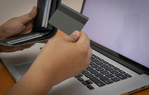 A man hand holding a credit card using a laptop to shopping online. Soft focus of young man of working using a laptop, Business concept, and communication technology. white blank screen