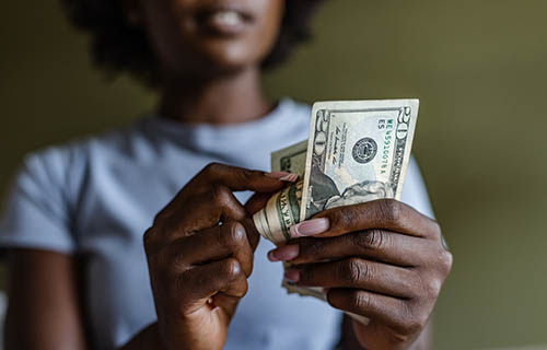 African American woman holding and counting dollars. Home budget planning.