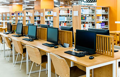 line of computers on desks in library