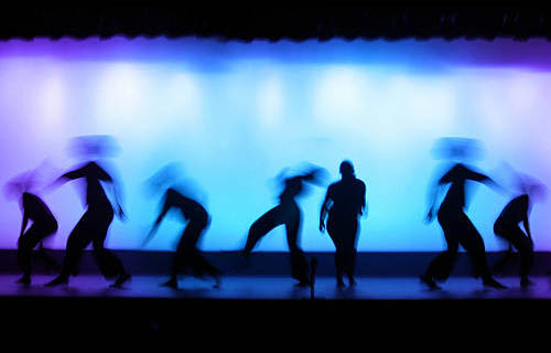 people dancing on a backlit stage