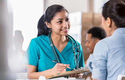 smiling young woman in medical smock with notepad