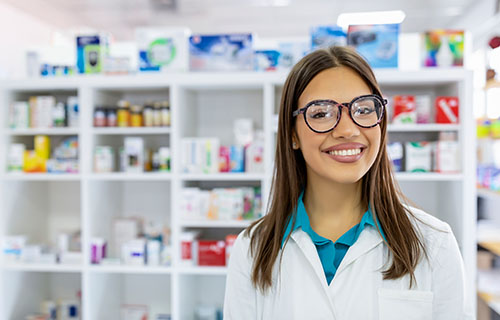 smiling young woman with white coat in pharmacy