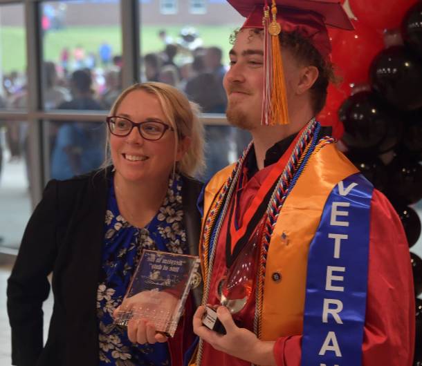 Toni Trimaur smiling and posing with a graduate for a photo