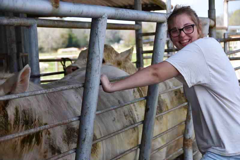 Woman standing next to a cattle pen and smiling