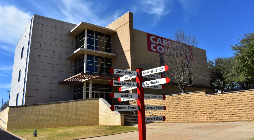 Exterior photo of the Tech Building with a campus directional sign in the foreground