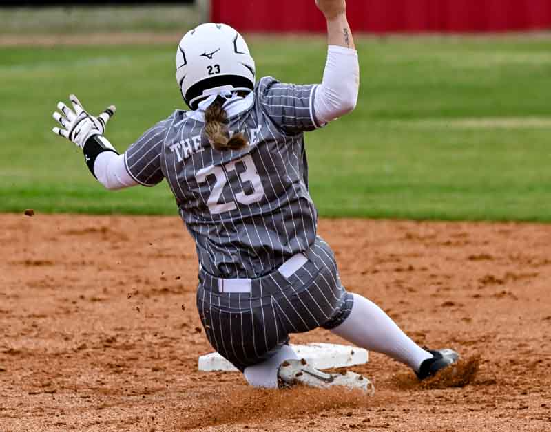 Woman softball athlete sliding to a base