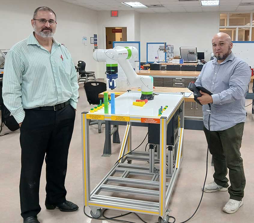 instructor and student standing next to a robot