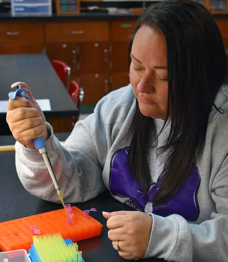 Female student using a pipette to fill test samples
