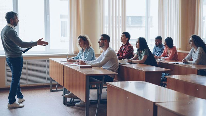 college students in a classroom attentively listening to their professor
