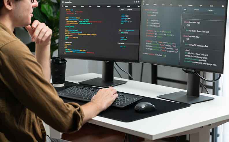 Man programming on a desktop computer with two screens