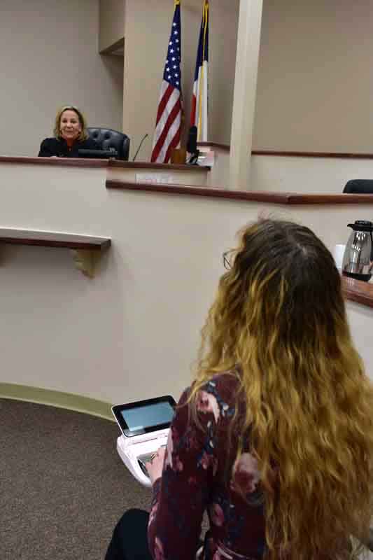 Judge in a court room smiling at the scopist