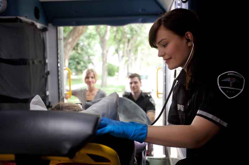 Paramedic in the back of an ambulance using a stethoscope on a child