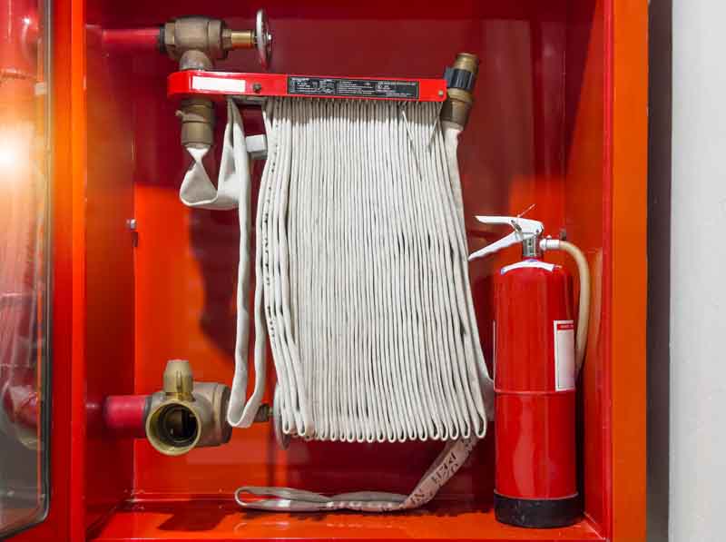 Fire hose rolled up next to a fire extinguisher