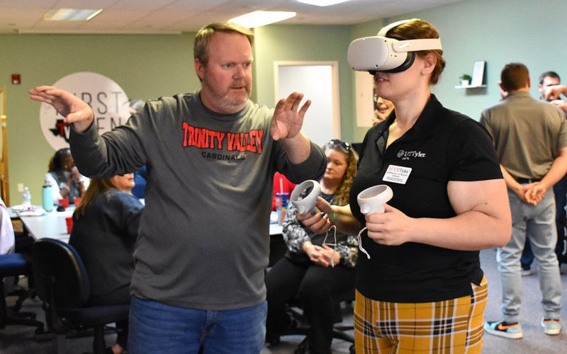 staff member showing a student how to use a VR headset