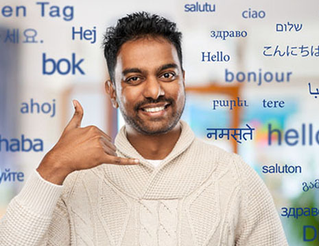 man gesturing his hand as a phone, words of different languages in the background