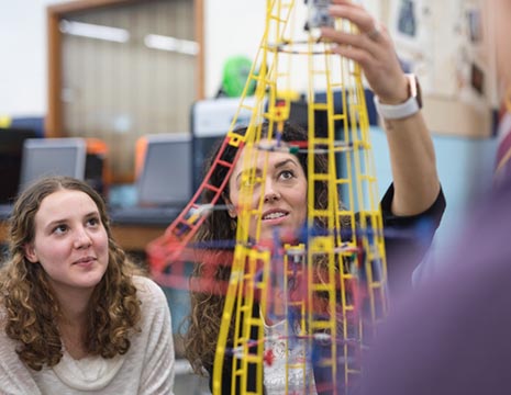 college-aged women working with physics manipulatives