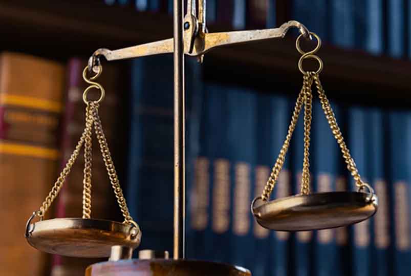 scales of justice in front of a bookshelf