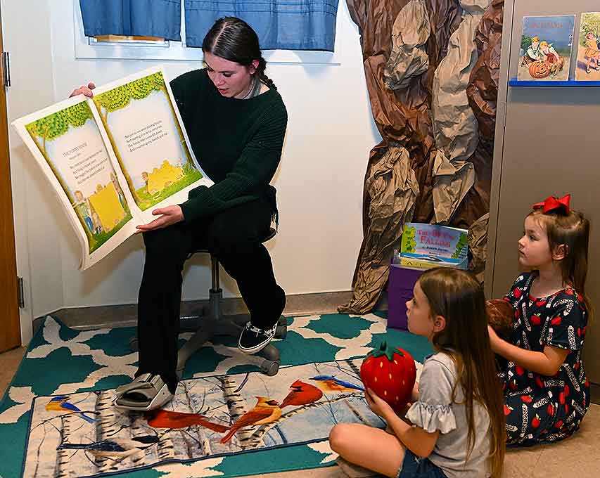 Student teacher reading a book to two little girls