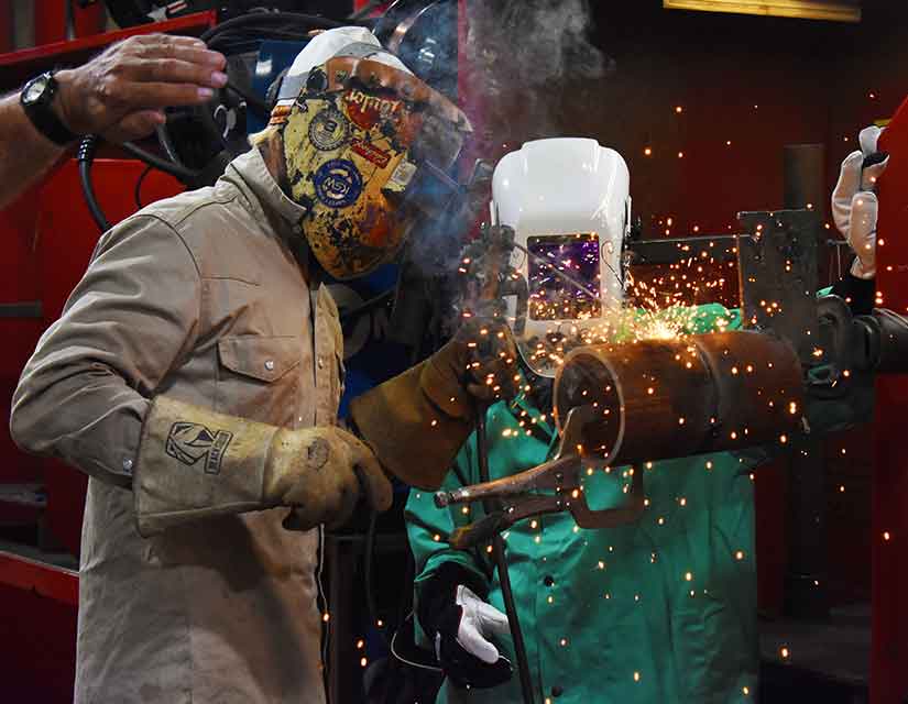 instructor and student welding a pipe