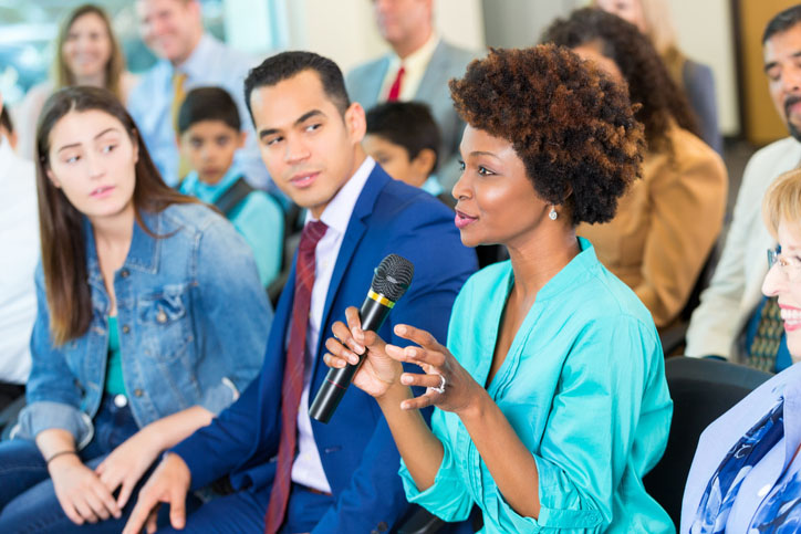 woman with microphone speaking from an audience