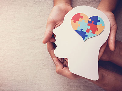 hands holding cardboard head cutout with heart-shaped brain