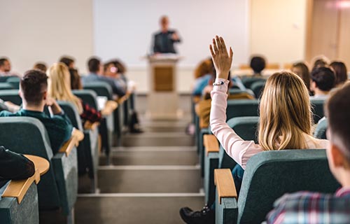 large classroom with student raising her hand