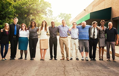 row of various-aged adults standing arm in arm