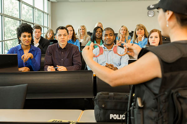 woman at front of large class holding handcuffs