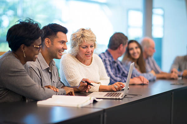 row of smiling men and women at a conference table